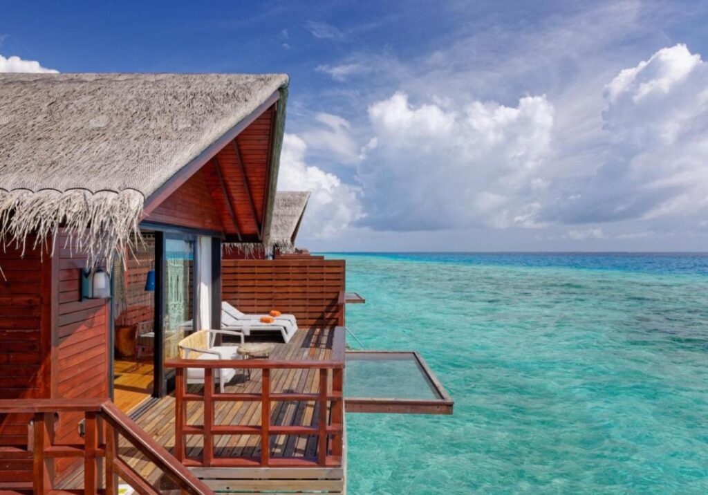 Overwater bungalows in the Maldives with panoramic ocean views under a golden sunset sky