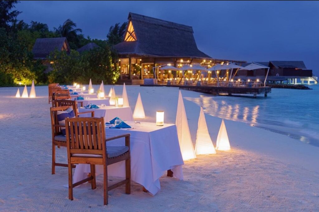 Romantic dinner setup on the beach in the Maldives with candles and ocean backdrop